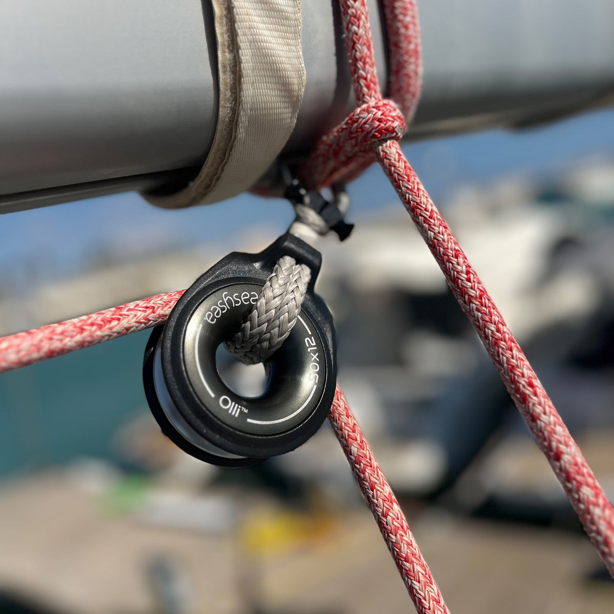 Olli anti-shock snatch block guiding a red line under the boom, marina in the background